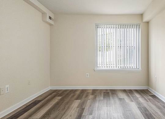 A room with a window and wooden flooring.