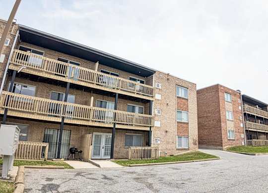 Apartment complex with brick buildings and a parking lot in front.