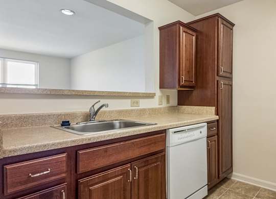 A kitchen with brown cabinets and a white dishwasher.