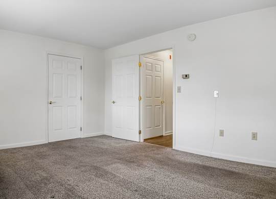 A room with a carpeted floor and two doors.