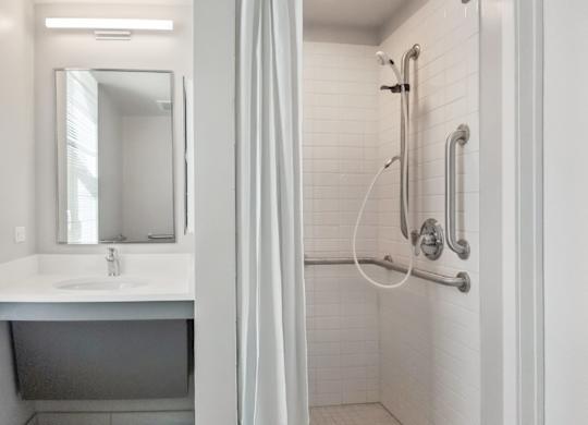 A white bathroom with a sink, mirror, and shower.