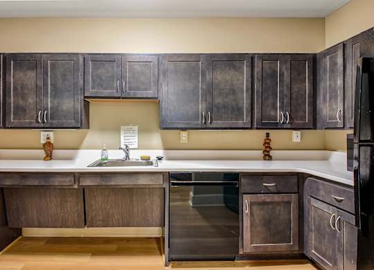 A kitchen with dark wood cabinets and a black refrigerator.