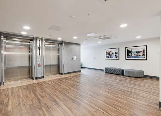 A hallway with wood floors and two elevators.