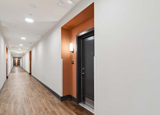 A long hallway with a black door on the right.
