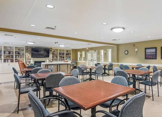 A room with tables and chairs and a television.