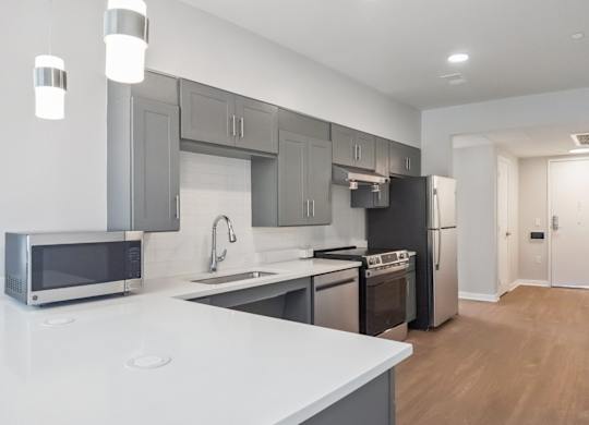 A modern kitchen with a white countertop and stainless steel appliances.