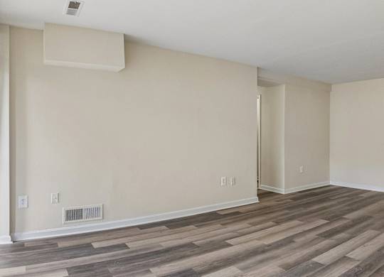 A room with wooden flooring and a wall-mounted air conditioning unit.