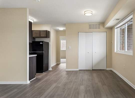 A spacious room with a white door and a black refrigerator.