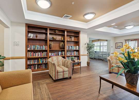 a seating area with couches and chairs and a bookshelf with books