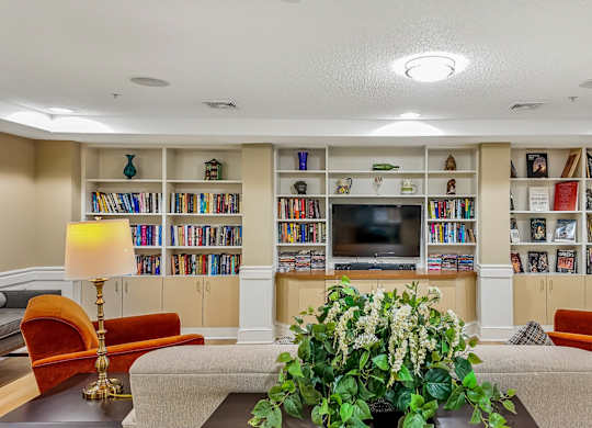 A living room with a large bookshelf filled with books and a flat screen TV mounted on the wall.