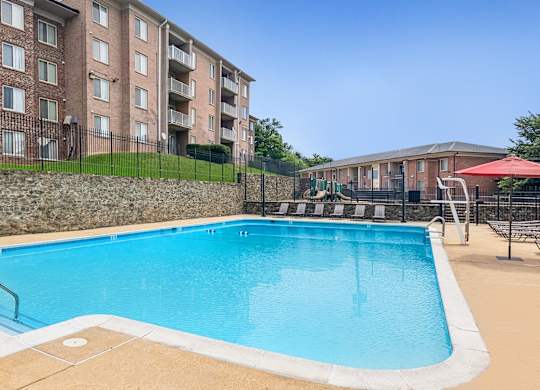 A swimming pool in front of a brick apartment building.