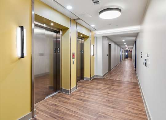 A long hallway with a yellow wall and wood flooring.