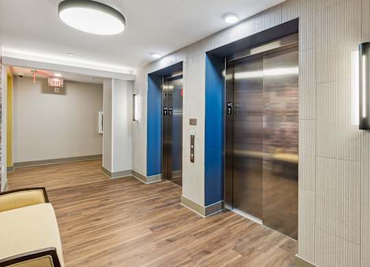 A hallway with two elevators, one blue and one silver.