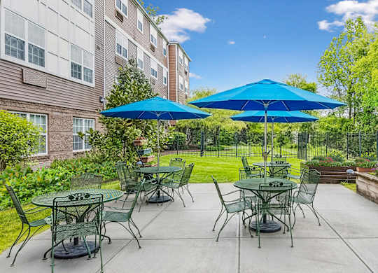 A patio with tables and chairs and umbrellas.