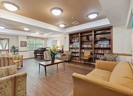 a room with couches chairs and a table with a vase of flowers and a piano