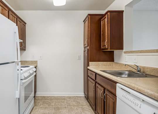 A kitchen with white appliances and brown cabinets.