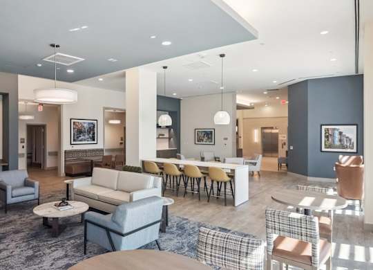 A spacious living room with a grey sofa set and a dining table with chairs.