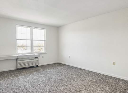 A room with a window and a wall-mounted air conditioner unit.