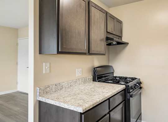 A kitchen with a black stove top oven and a counter top with a granite counter top.