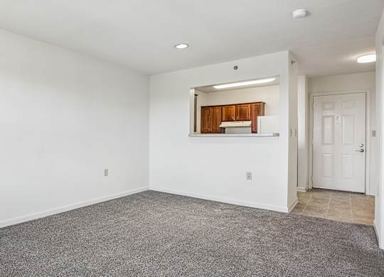 A spacious room with a carpeted floor and a door on the right side.