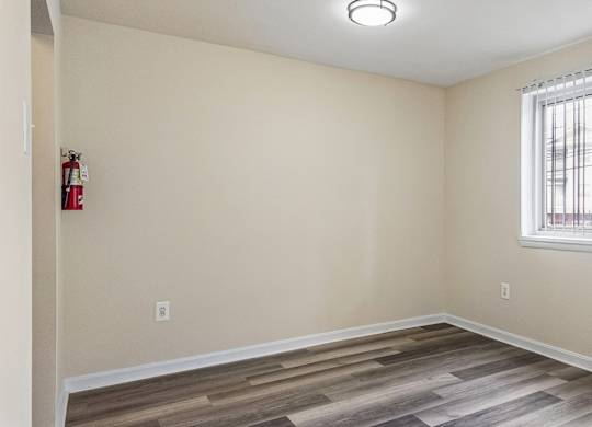A room with a fire extinguisher on the wall and a window with blinds.