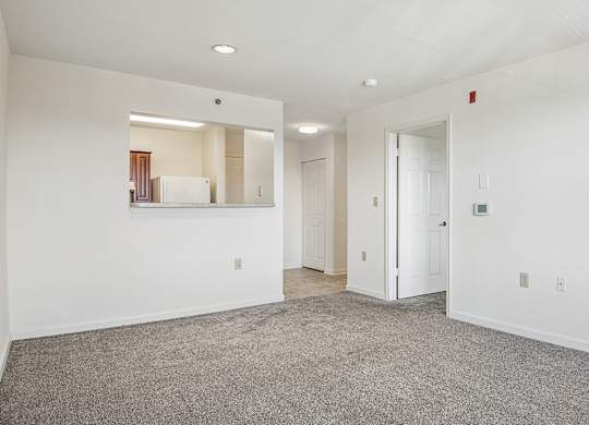 A spacious room with a carpeted floor and white walls.
