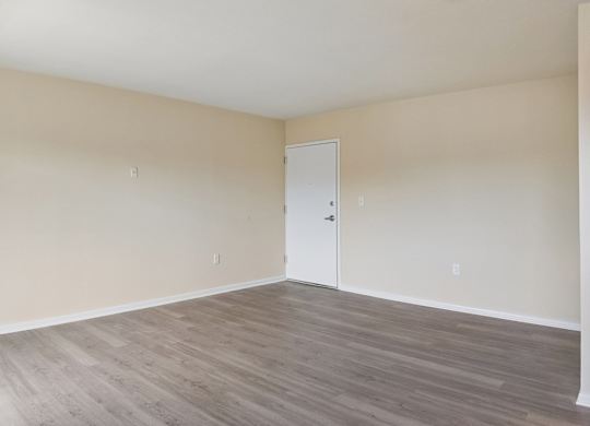 Empty room with wooden flooring and white walls.