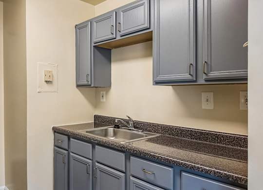A kitchen with blue cabinets and a white refrigerator.