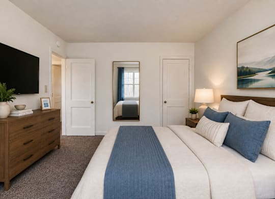 A bedroom with a large bed and a wooden dresser.