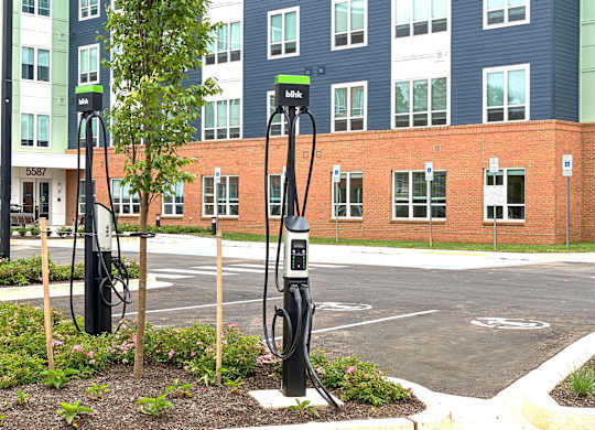 Three electric vehicle charging stations in front of a building.