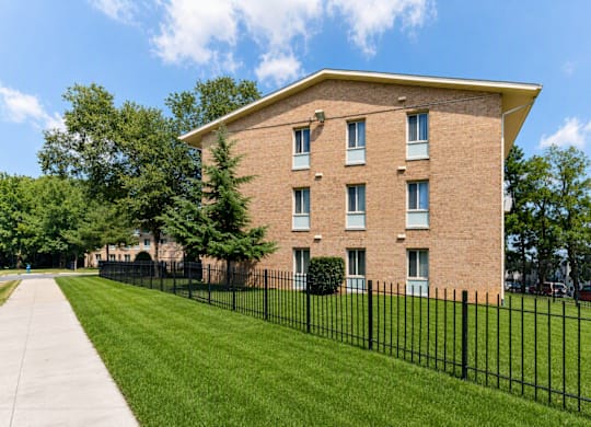 A brick building with a black fence in front.