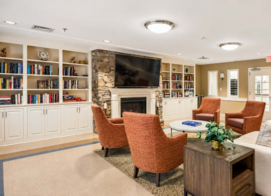 A living room with a fireplace, chairs, and a bookshelf.