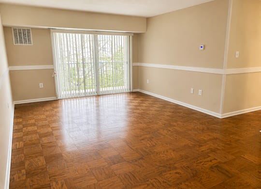 A room with wooden flooring and a sliding glass door.