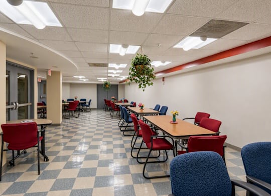 A long table with red chairs is in a room with a checkered floor.