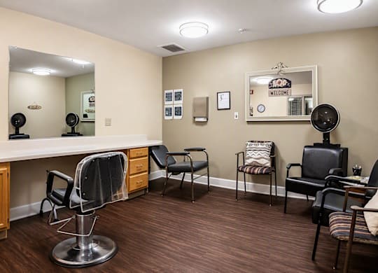 A hair salon with chairs and a mirror.