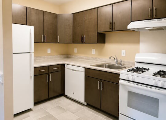 A kitchen with white appliances and brown cabinets.