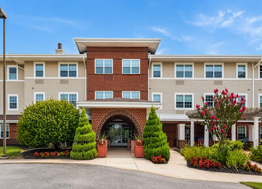 A large building with a red brick entrance and a landscaped front yard.