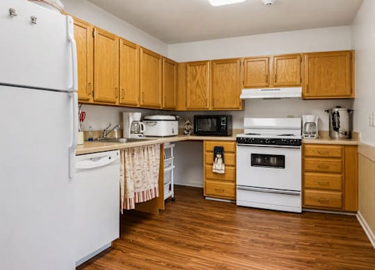 A community kitchen with wooden cabinets and white appliances.