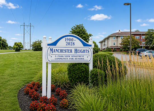 A sign for Manchester Heights Apartments stands in front of a grassy area.