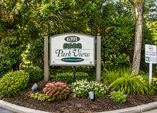 A sign for Park View is surrounded by flowers and trees.