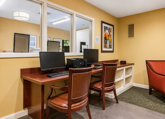 A room with a desk and chairs and a laptop on it.