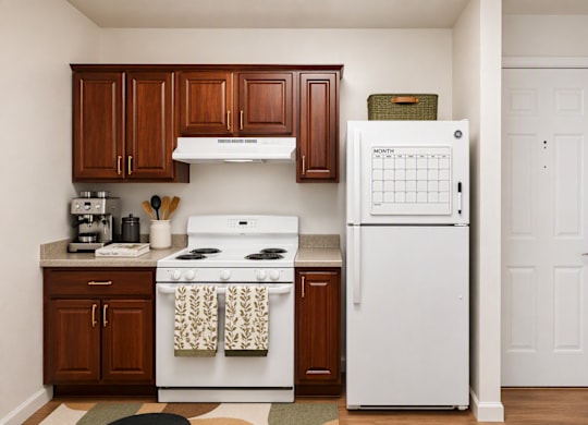 A white stove and refrigerator in a kitchen with brown cabinets.