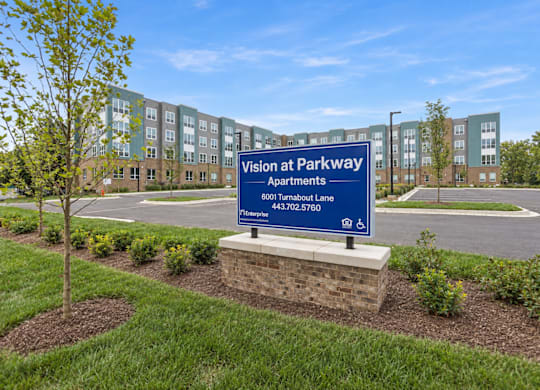 A sign for Vision at Parkway Apartments is in front of a building.