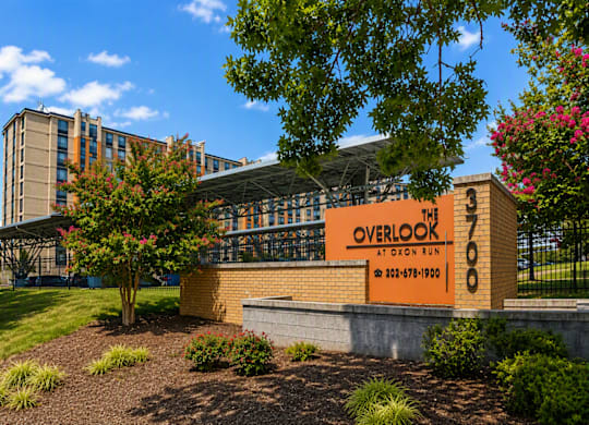 A building with a sign that reads "Overlook" is surrounded by trees and shrubs.