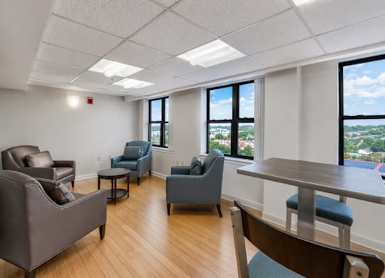 A room with a table, chairs and a view of the city.