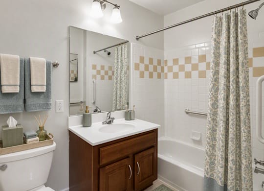 A bathroom with a white tub and a sink with a wooden cabinet.