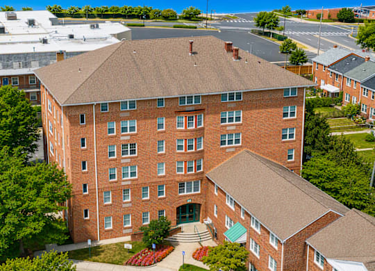 A large red brick building with a green roof and a courtyard in front.