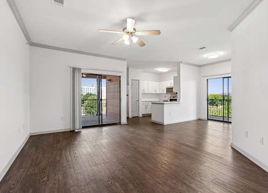 A spacious living room with a ceiling fan and hardwood floors.