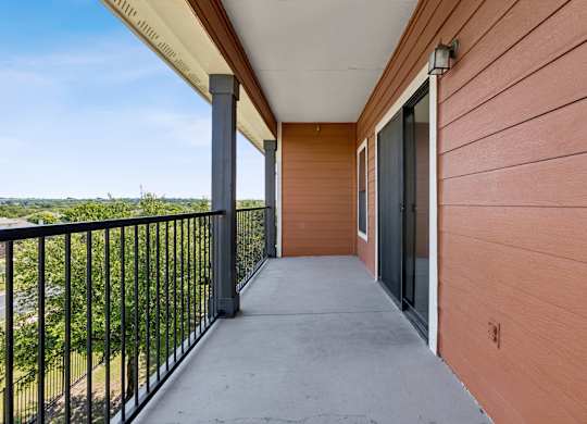 A balcony with a black railing and a view of the outdoors.