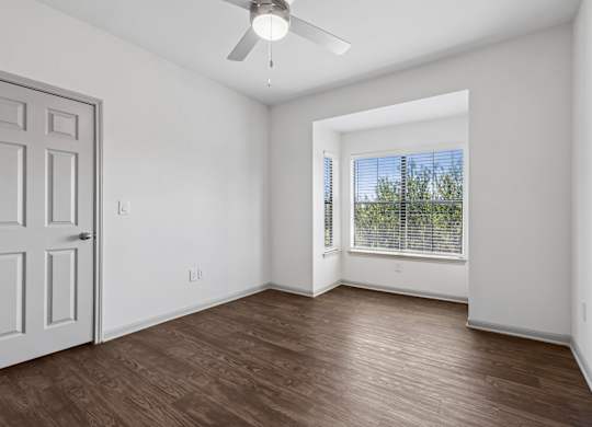 A room with a ceiling fan and a door.